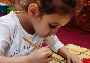 Dziewczynka malująca farbami akwarelowymi.