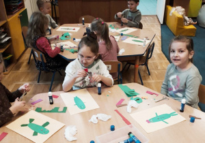Dzieci przy stoliku wykonują pracę plastyczną "Zielony ogórek".