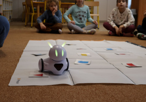 Robot na macie do kodowania, pokonuje trase zaprogramowana przez dzieci