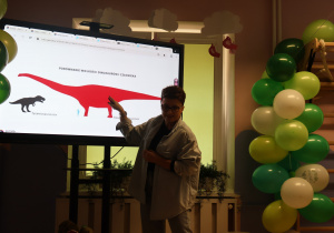 Prowadząca zajęcia opowiada dzieciom o dinozaurach.