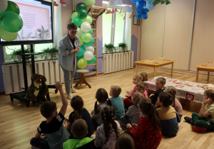 Prowadząca zajęcia opowiada dzieciom o dinozaurach.