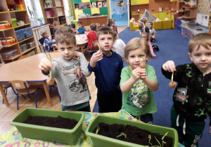 Dzieci sadzące cebulę w donicy z ziemią.
