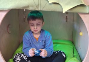 chłopiec bawi się gniotkiem w kryjówce