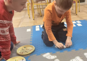 dzieci rozwiązuja zadanie na dywanie