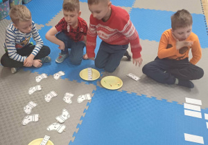 dzieci rozwiązuja zadanie na dywanie