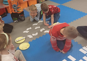 dzieci rozwiązuja zadanie na dywanie