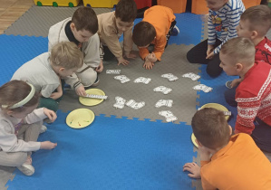 dzieci rozwiązuja zadanie na dywanie
