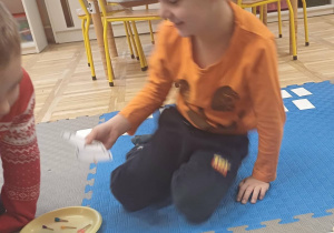 dzieci rozwiązuja zadanie na dywanie