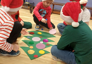 dzieci ubierają kartonową choinkę