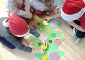 dzieci ubierają kartonową choinkę