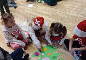 dzieci ubierają kartonową choinkę