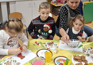 dzieci z rodzicami zdobią pierniczki